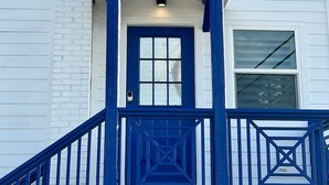 Un edificio blanco con un porche azul y una puerta central.
