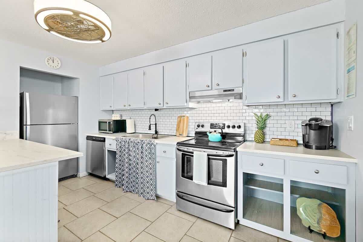 A modern kitchen with white cabinets, stainless steel appliances, and a tiled backsplash.