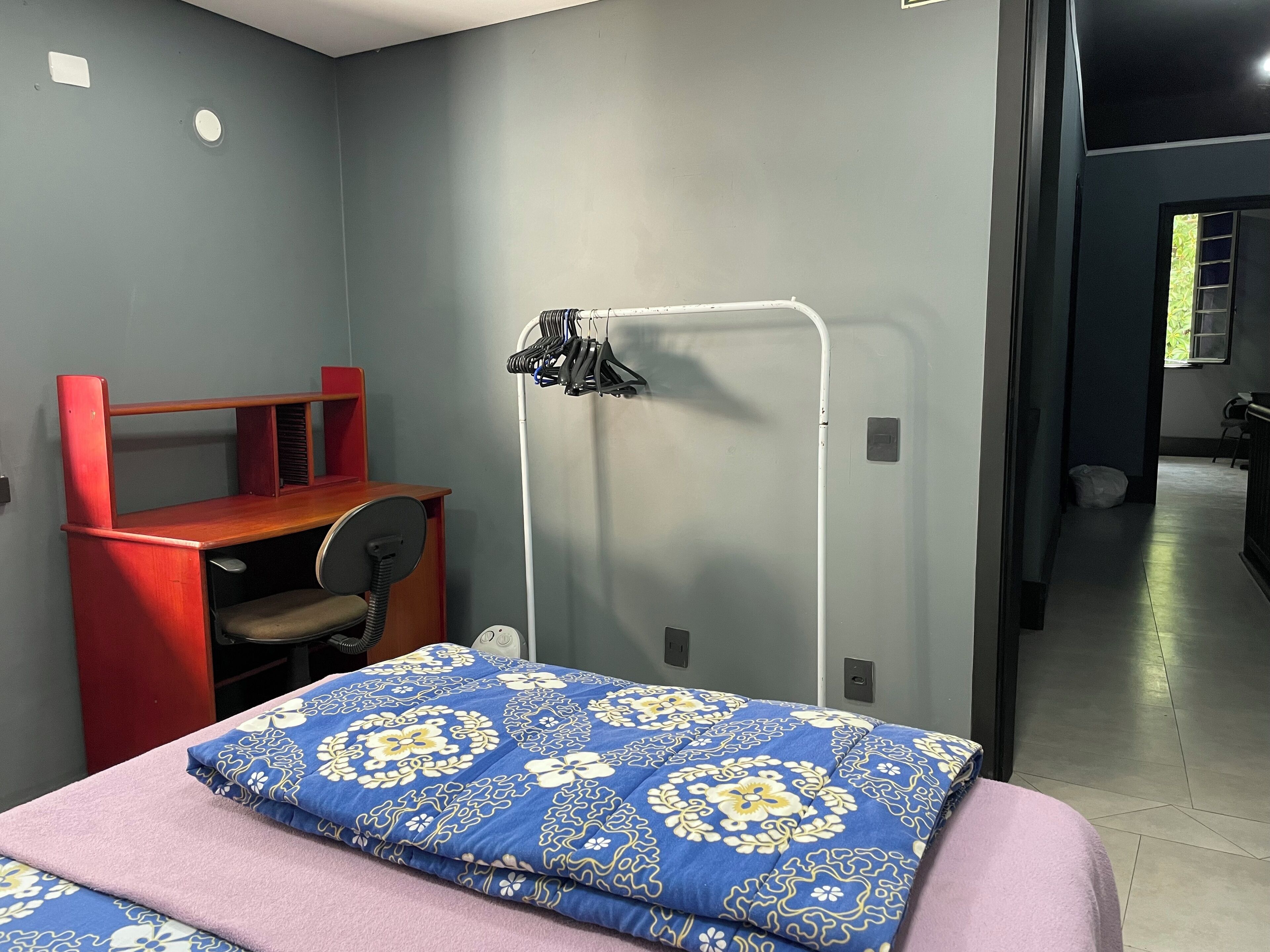 A bedroom with a bed, a desk, and a chair.