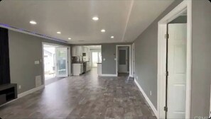 Un hall d  ’entrée spacieux, doté d’un plancher en bois, de luminaires encastrés au plafond et d’une porte située sur le côté droit.