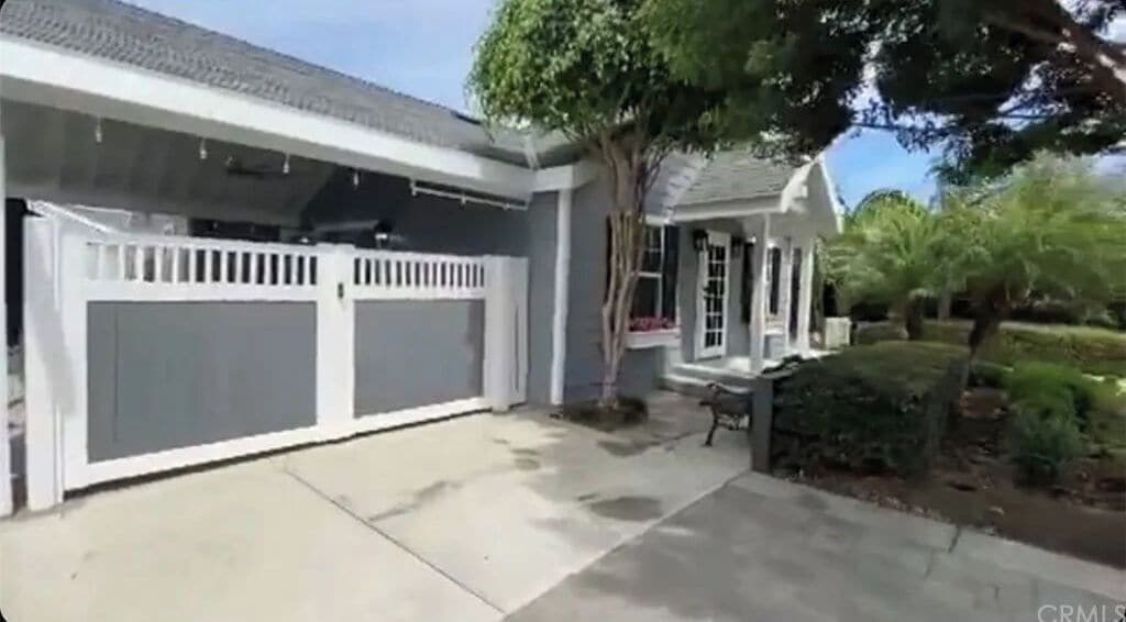 Een woonhuis met garage, overdekte veranda en een verzorgd gazon.