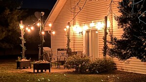 Une maison avec un porche, des guirlandes lumineuses et du mobilier d’extérieur.
