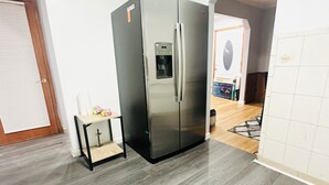 Eine moderne Küche mit einem Edelstahl-Kühlschrank, einem kleinen Holztisch und einer gefliesten Spritzschutzwand.