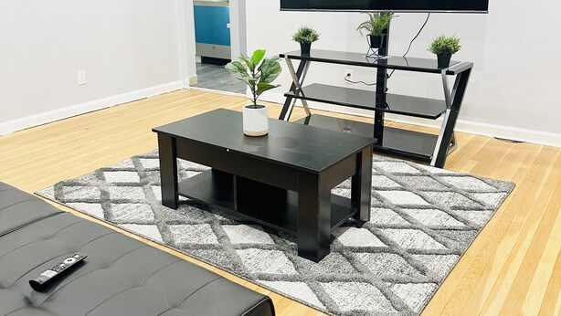 Ein modernes Wohnzimmer mit einem schwarzen Sofa, einem Couchtisch und einem Fernseher auf einem Schrank.