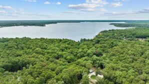 An aerial view of a forested area with a lake and a clear sky.