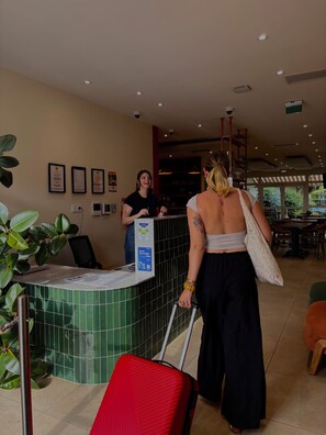 A reception area with a counter, a plant, and a red suitcase. - HOSHO - Bordeaux Centre Victoire (Bordeaux)