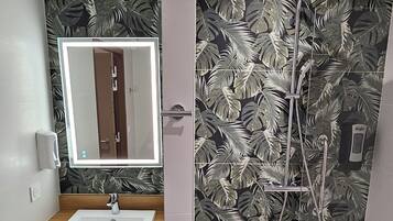 A bathroom with a wooden vanity, a mirror, a shower with a rain showerhead, and a toilet.
