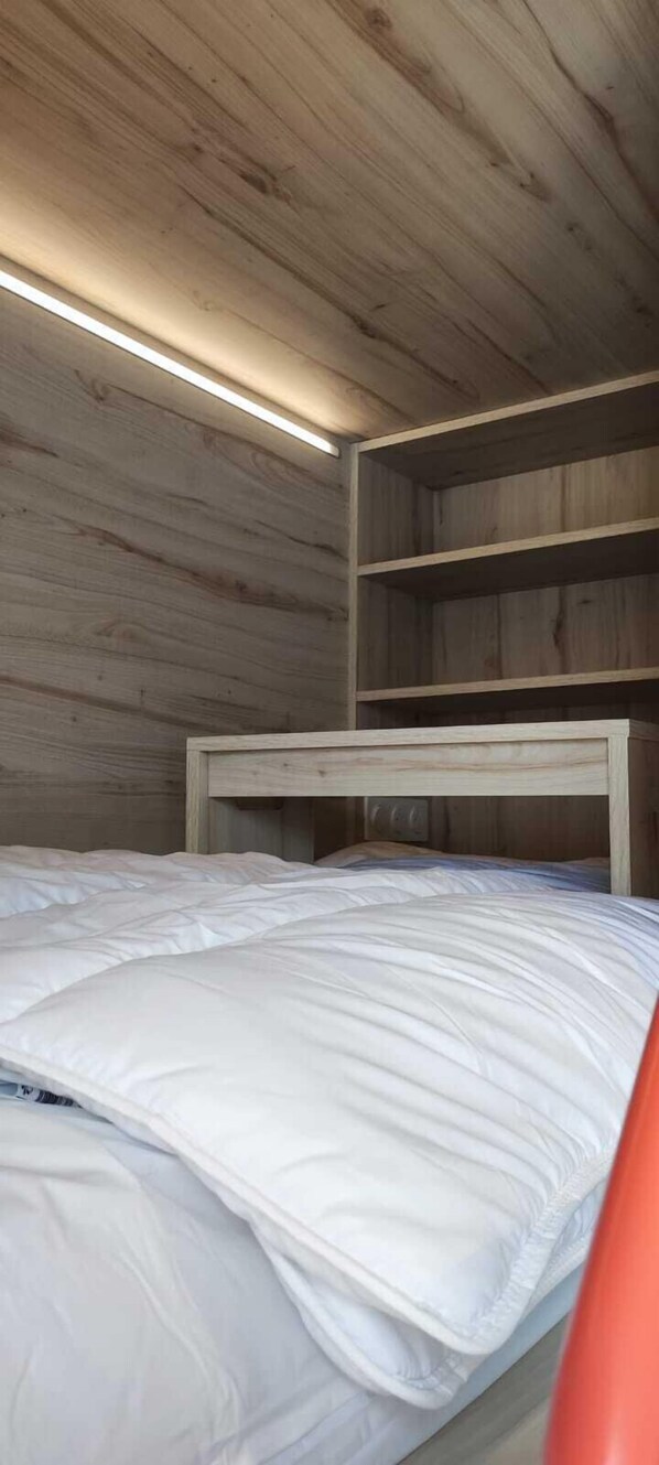 Una cama litera de madera con colchón blanco y cabecera.