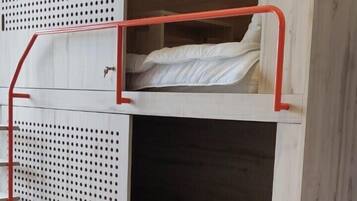 Una cama litera con escalera, cajones y un panel perforado.