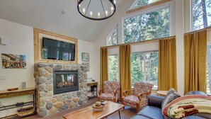 A cozy living room with a stone fireplace, comfortable seating, and large windows offering a view of the outdoors. - Unwind in Cle Elum: Hot Tub & Cozy Fireplace! (Cle Elum)