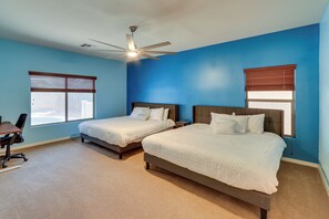 Une chambre avec deux lits, un bureau et un ventilateur de plafond.