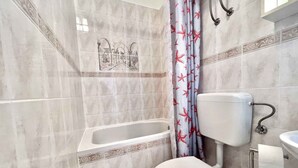 A bathroom with a bathtub, toilet, and sink.