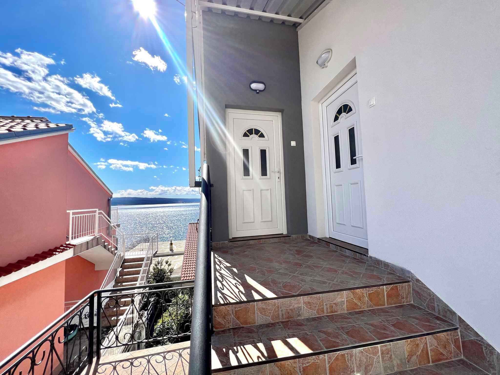 A staircase leading to a white door with a view of the sea.