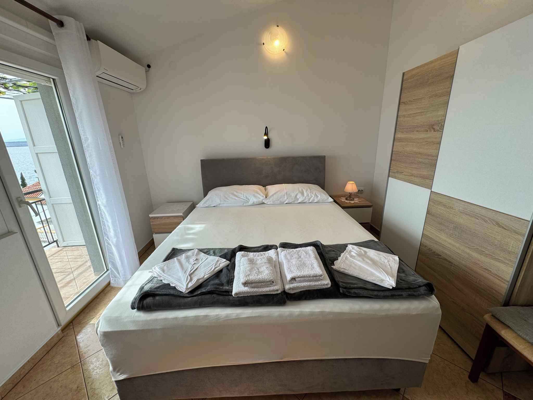 Un dormitorio moderno con cama, mesitas de noche y vistas al exterior.