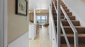 A staircase with carpeted steps and a railing, leading to a balcony with a view.