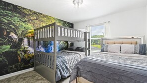 Cozy retreat with a bunk bed and single bed, featuring a large window and vibrant forest-themed wallpaper.