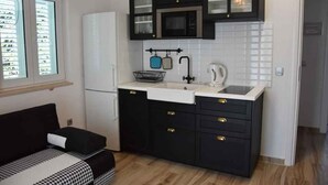 A compact kitchen with black cabinets, a white sink, and a microwave. - Holiday apartment with sea view and terrace (Orebić)