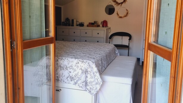 A bedroom with a bed, a bedside table, a dresser, and a chair. - -Le Carillon- Romantic and cozy Suite with Jacuzzi 2 steps from Bergamo (Sorisole)