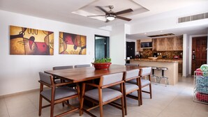 A dining area with a wooden table and chairs, a ceiling fan, and abstract wall art. - Fantastic Family Villa on the best Beach in Cancun (CancÃºn)