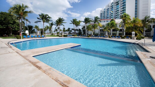 A swimming pool with clear blue water, surrounded by palm trees and lounge chairs. - Fantastic Family Villa on the best Beach in Cancun (CancÃºn)