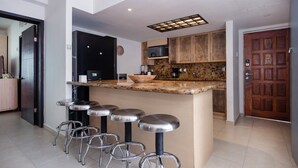 A modern kitchen with a central island, bar stools, wooden cabinets, and a built-in oven. - Fantastic Family Villa on the best Beach in Cancun (CancÃºn)