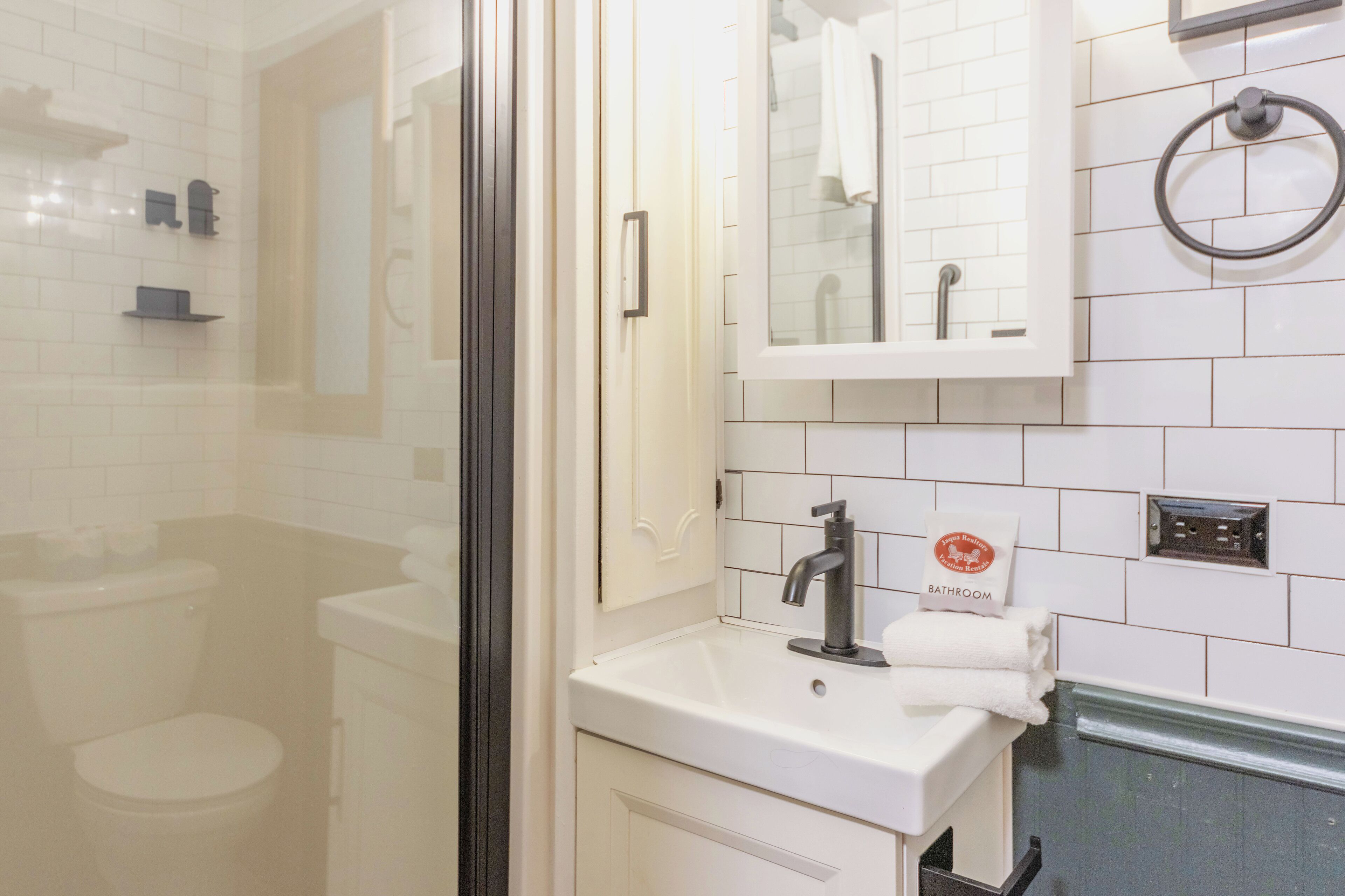 Baño con lavamanos blanco, espejo y toallero.