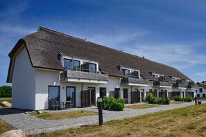 A row of modern, two-story buildings with thatched roofs and white exteriors.