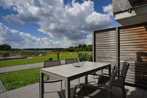 An outdoor patio with a table and chairs, a view of a lake, and a wooden fence.