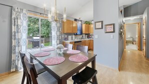 Una cocina moderna con armarios de madera, una mesa de comedor con manteles individuales rosas y vistas al exterior.