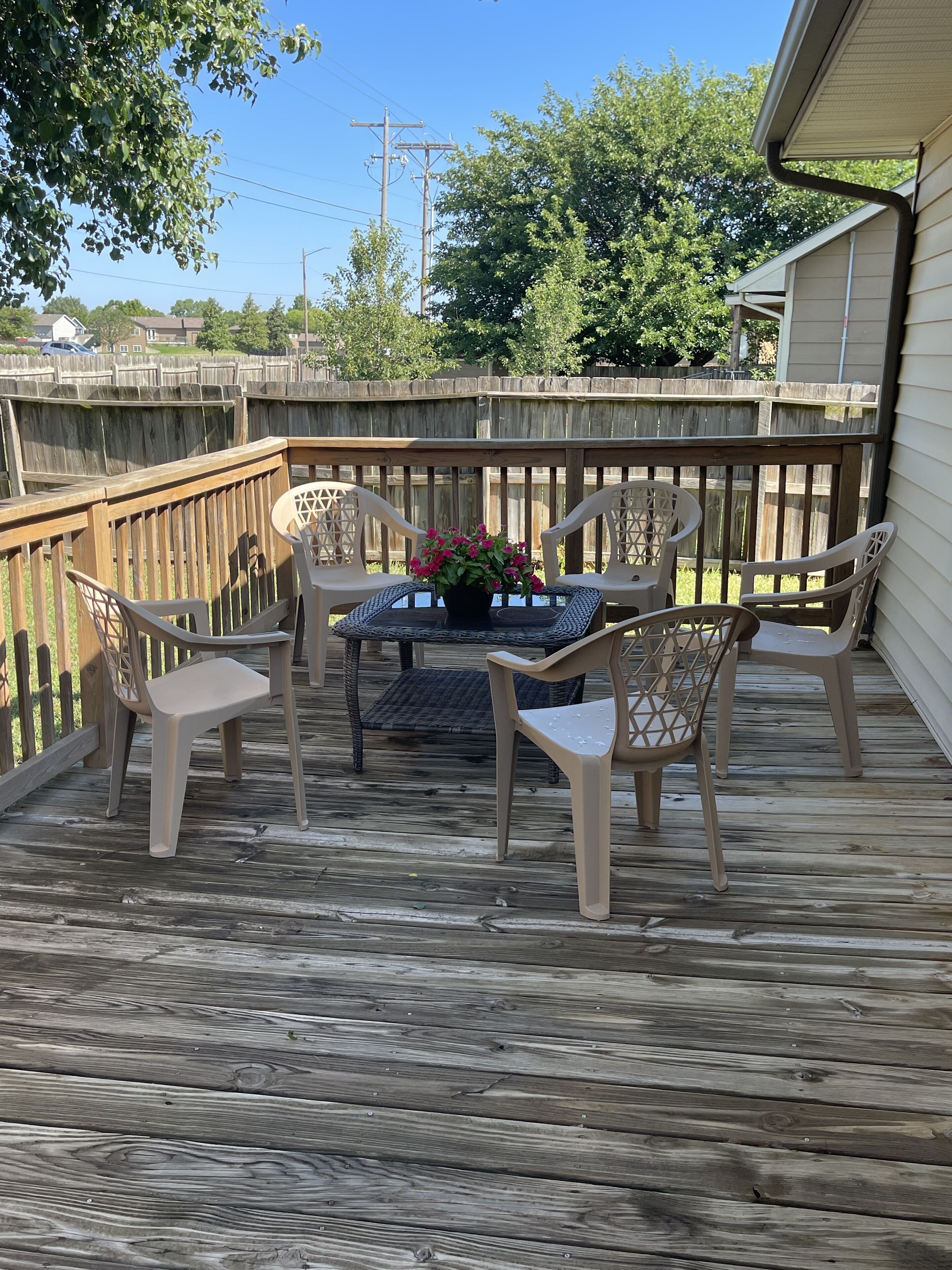 A wooden deck with a table and chairs, surrounded by a wooden fence.