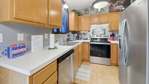 Una cocina moderna con armarios de madera, electrodomésticos de acero inoxidable y encimera blanca.