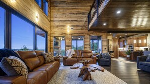 Ein großzügiges Wohnzimmer mit Ledersofas, einem Holztisch und großen Fenstern mit Blick ins Freie.