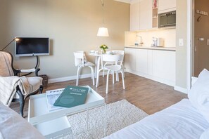 Una sala de estar moderna con un sofá, una mesa de centro con libros, un televisor y un comedor con sillas y una mesa.