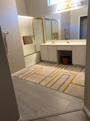 Un baño con ducha, lavamanos y espejo.