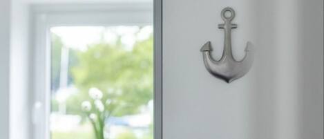 A white door with a metal anchor decoration.