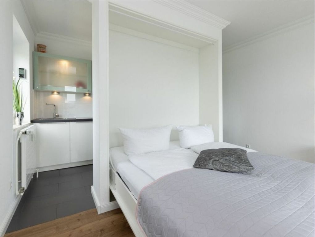Une chambre à coucher comprenant un lit, une table de chevet et une armoire intégrée.
