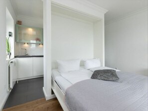 A bedroom with a bed, a bedside table, and a built-in wardrobe.