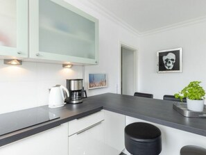 A modern kitchen with a dark countertop, white cabinets, a coffee maker, and a potted plant. - Seetempel - Modernes 37 qm 1-zimmer-apartment mit Südwest-balkon und Direkter Strandlage (Scharbeutz)