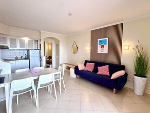 A compact living space with a kitchenette, a dining area, a sofa, and a potted plant.