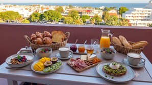 Une table de petit-déjeuner avec divers aliments et une vue sur la ville et la mer.