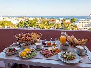 Une table de petit-déjeuner avec divers aliments et une vue sur la ville et la mer.