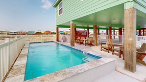 Une piscine dotée d’une terrasse en bois et de chaises longues, le tout entouré d’une clôture blanche.