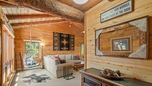 A cozy log cabin interior with a sofa, a rocking chair, a wooden table, and a sign on the wall. - Modern Log Cabin, Great Deck, 10 min from Durango! (Durango)
