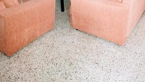 Een woonkamer met een perzikkleurige zithoek, een salontafel en een plafondventilator.