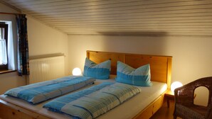 Ein Doppelbett mit Holz Kopfteil, zwei Nachttischlampen und ein Korbstuhl.