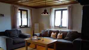 Ein Wohnzimmer mit Holzboden, zwei Sofas, einem Couchtisch und einer Pendelleuchte.