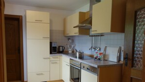 Eine kleine Küche mit weißen Schränken, einem Einbauofen, einer Kaffeemaschine und einem Toaster.