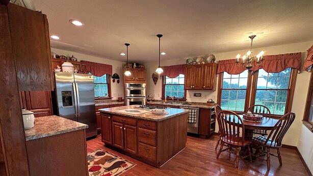 A spacious kitchen with wooden cabinets, a central island, and a dining area with a table and chairs.