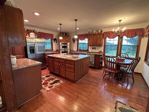 Una cocina amplia con armarios de madera, una isla central y una zona de comedor con mesa y sillas.