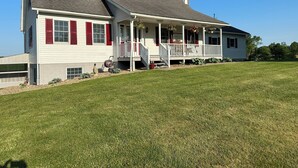 A two-story house with a porch, a chimney, and a well-maintained lawn.